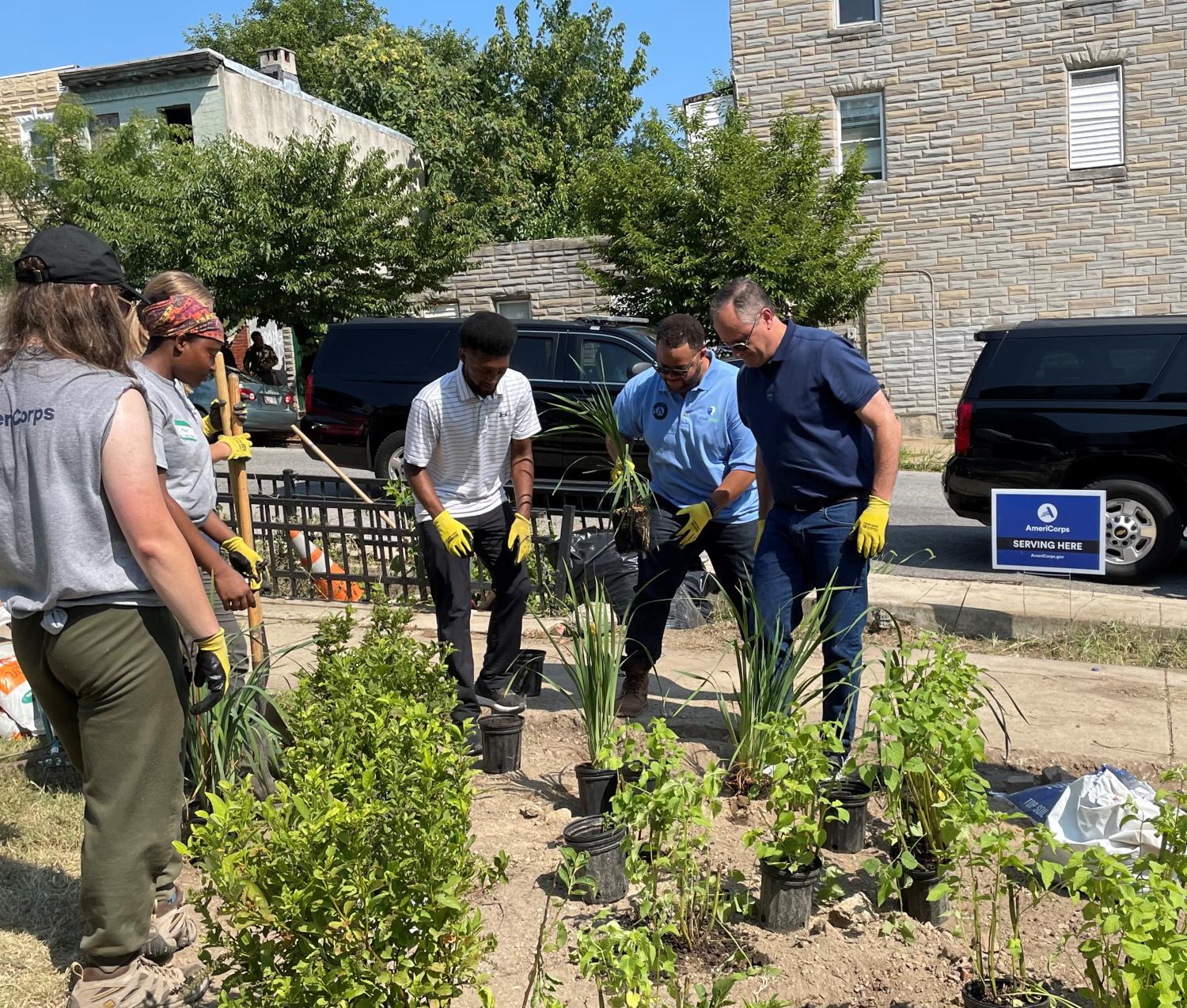 Second Gentleman Douglas Emhoff, AmeriCorps CEO Michael D. Smith and Baltimore Mayor Brandon Scott plant trees with Civic Works AmeriCorps Members in Baltimore.