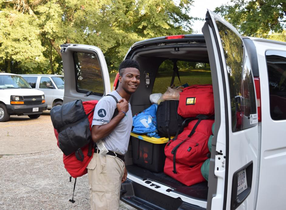 Man standing in front of an open van wearing a backpack